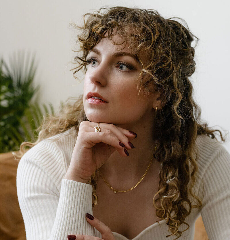 Hannah looking to the side resting her face on her hand.