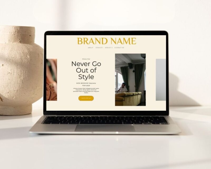 A laptop displaying a minimalist Free Showit website template with a neutral background, bold yellow headline reading “Brand Name,” and a centered section with the text “Never Go Out of Style.” The layout includes images, navigation links, and a call-to-action button that says “Work With Us.”
